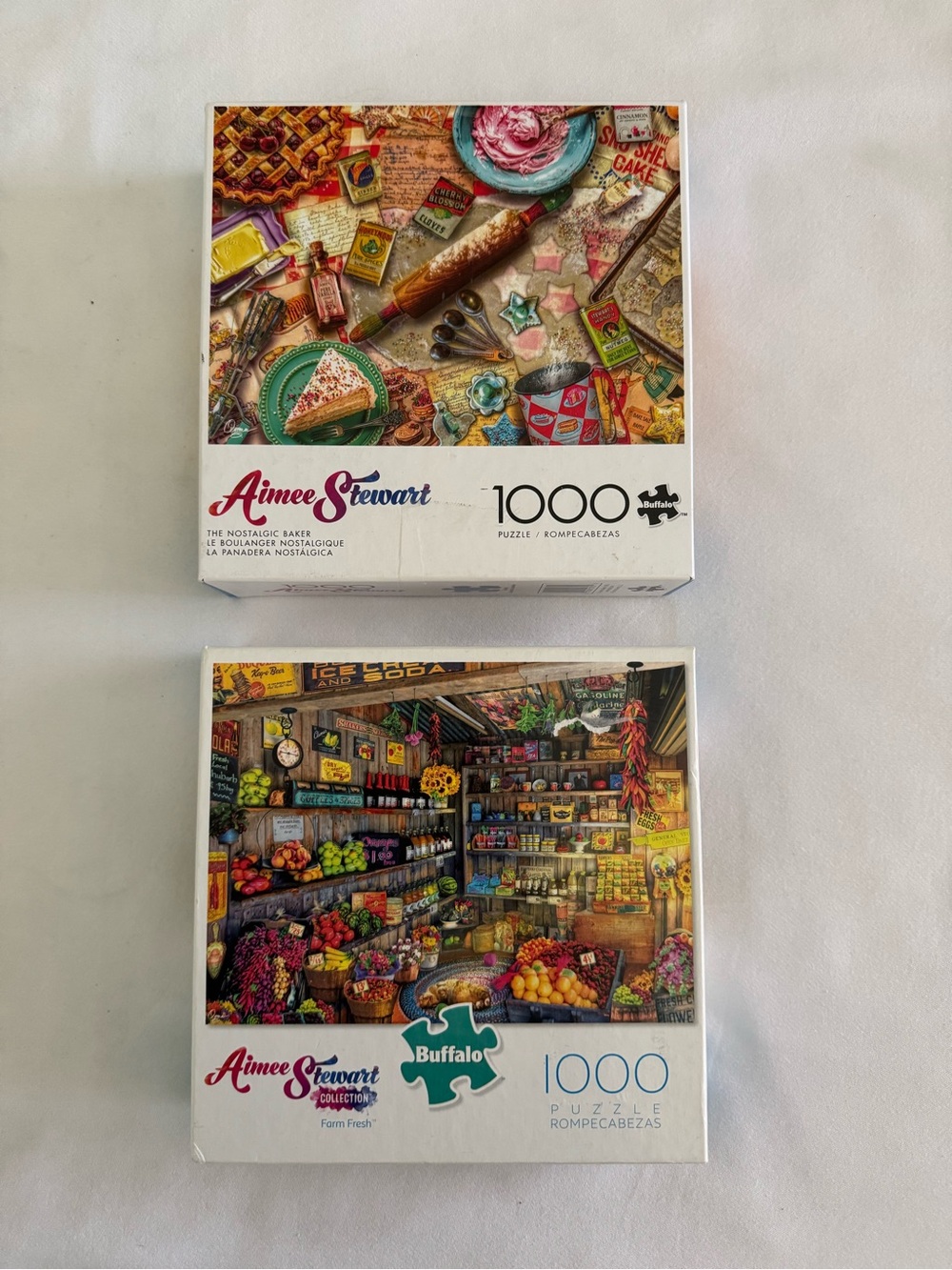 Two 1000 piece Buffalo puzzles by Aimee Stewart.  Finished size 26.75" x 19.75".